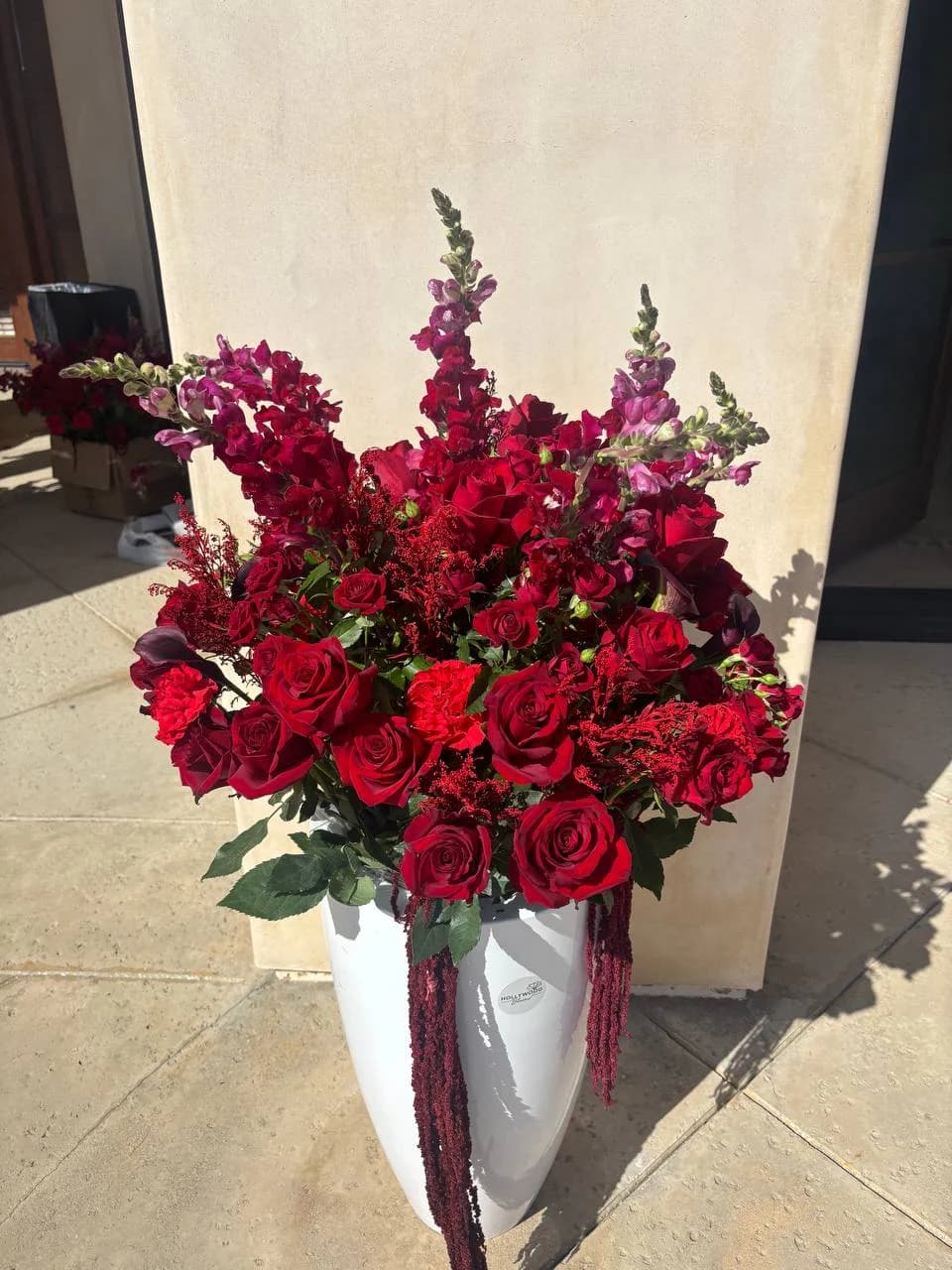 Sculptural red rose arrangement in a tall white vase